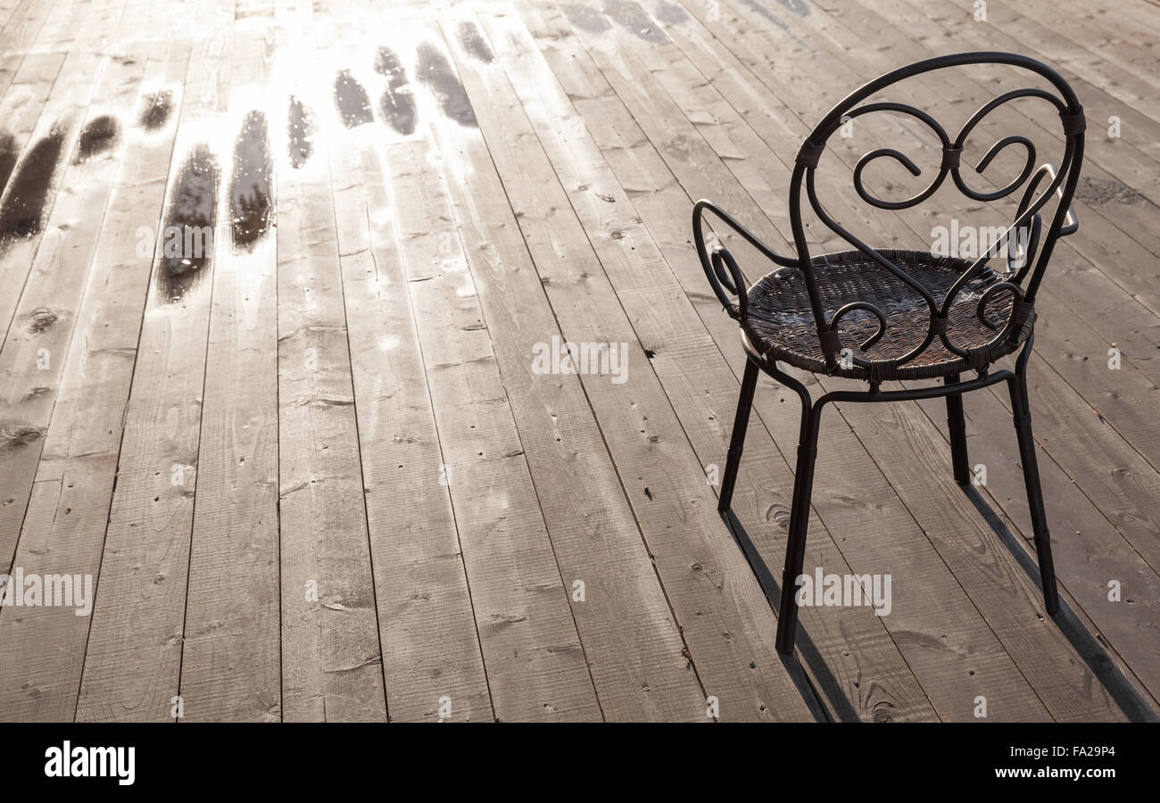 Vecchio nero ferro battuto sedia in piedi sul pavimento di legno, foto all'aperto Foto Stock