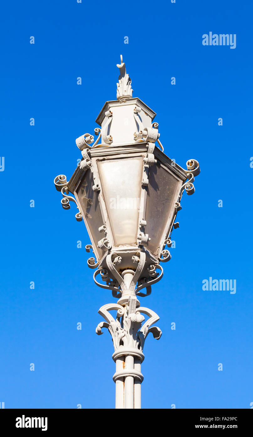 Vecchio stile strada bianca lampada con letti in ferro battuto con decorazioni blu su sfondo cielo Foto Stock