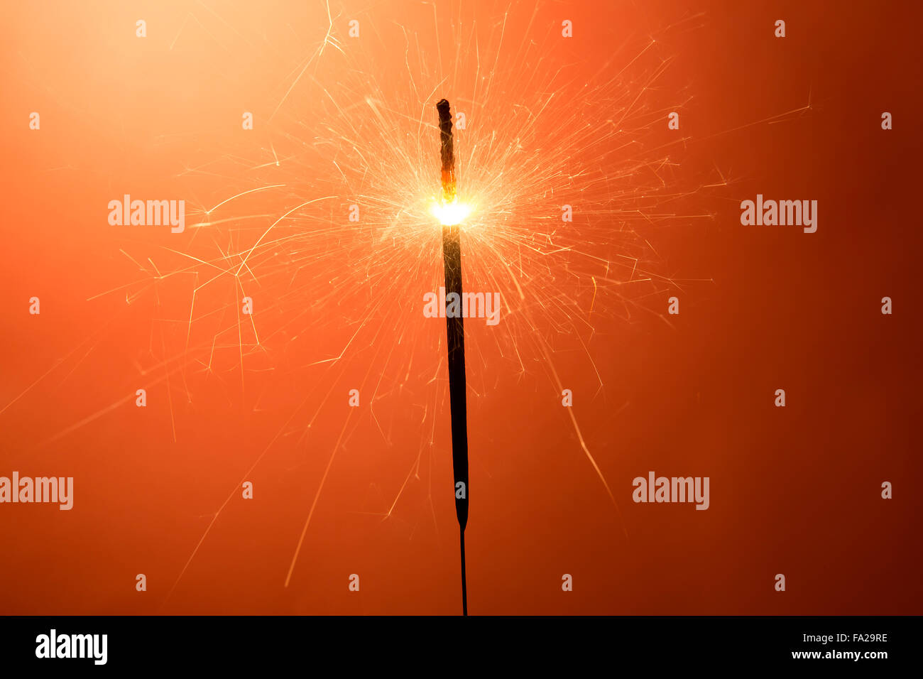 Burning sparkler davanti a uno sfondo arancione Foto Stock