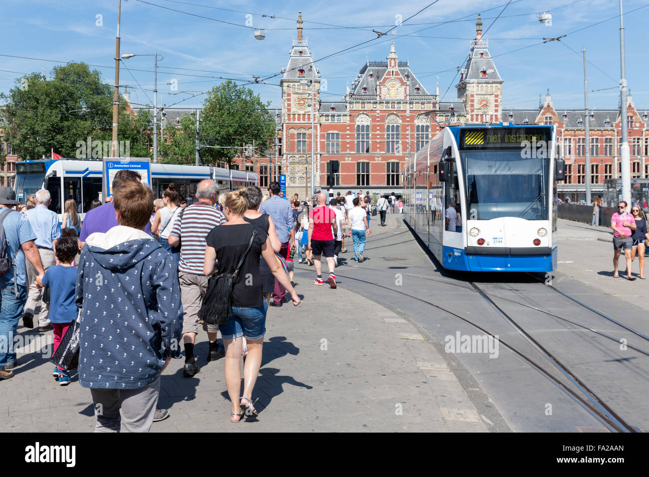 AMSTERDAM, PAESI BASSI - agosto 06: i turisti a piedi di fronte alla stazione centrale di Amsterdam vicino a una fermata del tram Foto Stock