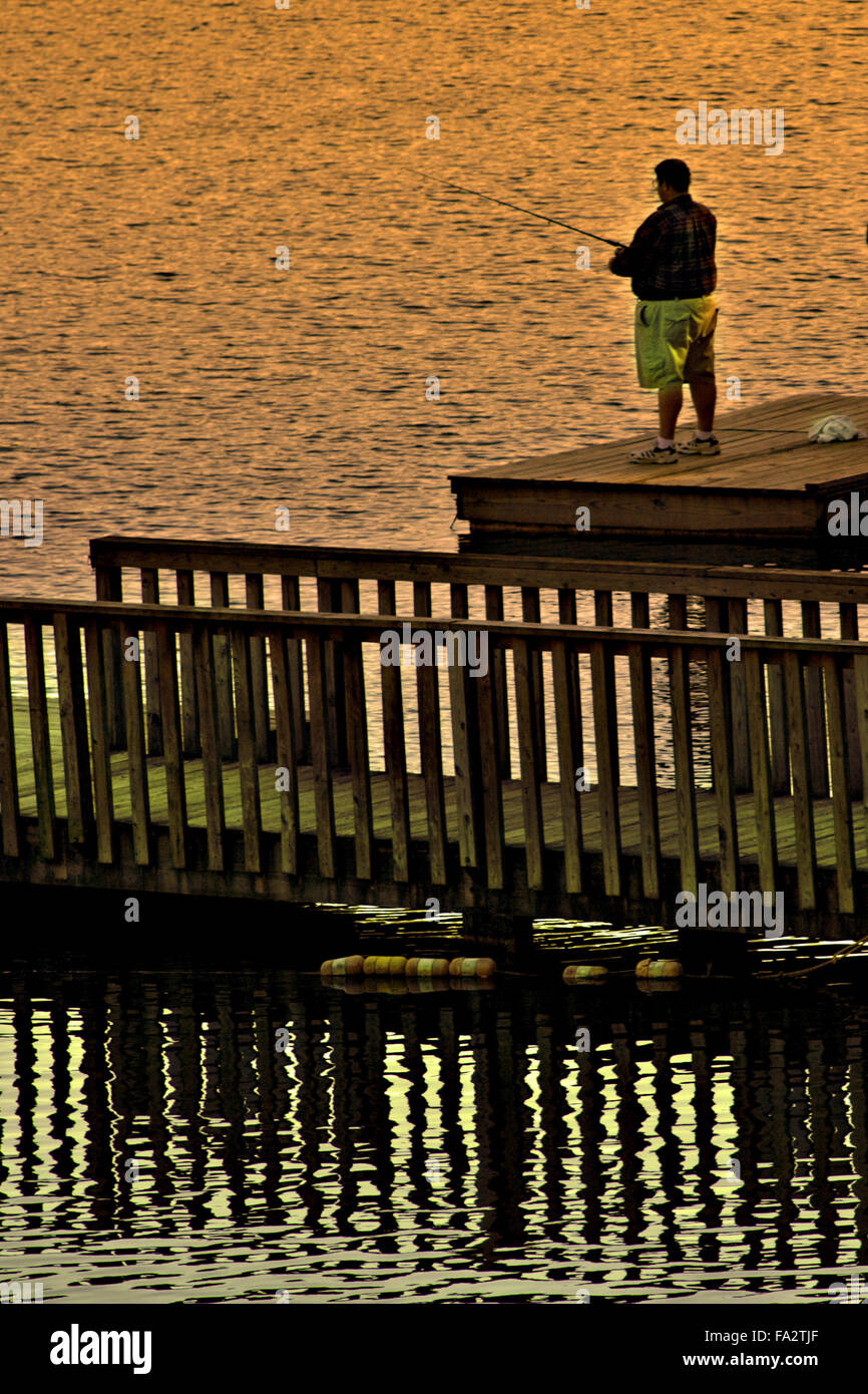 Pescatore su una dock al tramonto. Foto Stock