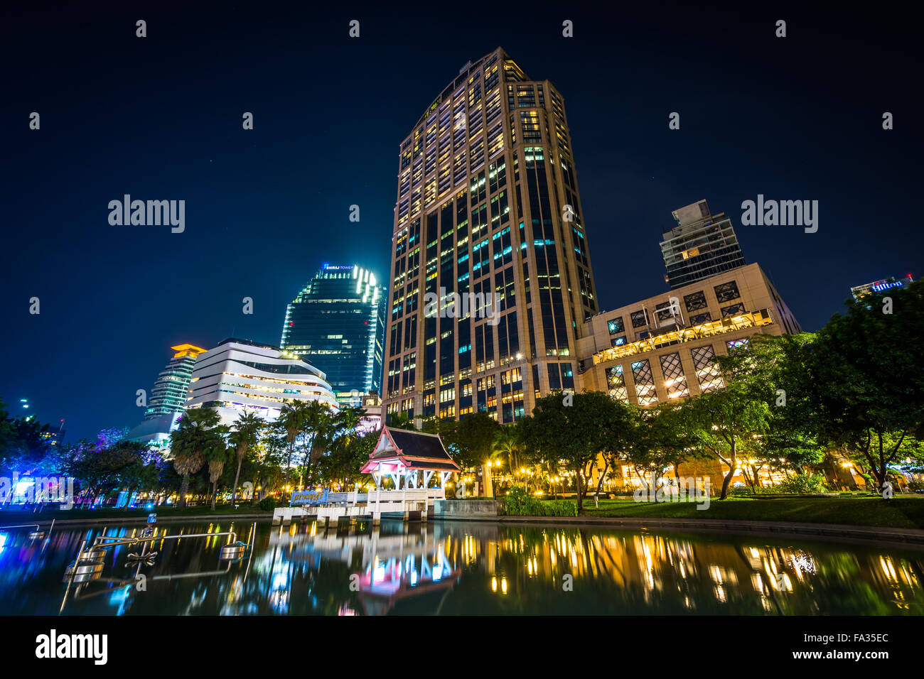 I moderni grattacieli e lago di notte, visto al Parco di Benjasiri, Bangkok, Tailandia. Foto Stock