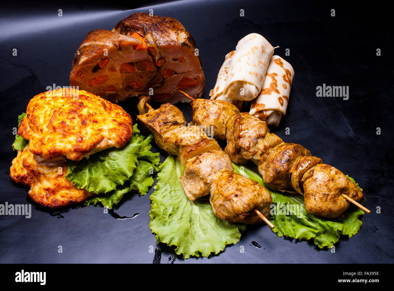 Still Life - carne con ripieni, shish kebab, bistecca in pastella, crepes con riempimenti su sfondo nero Foto Stock