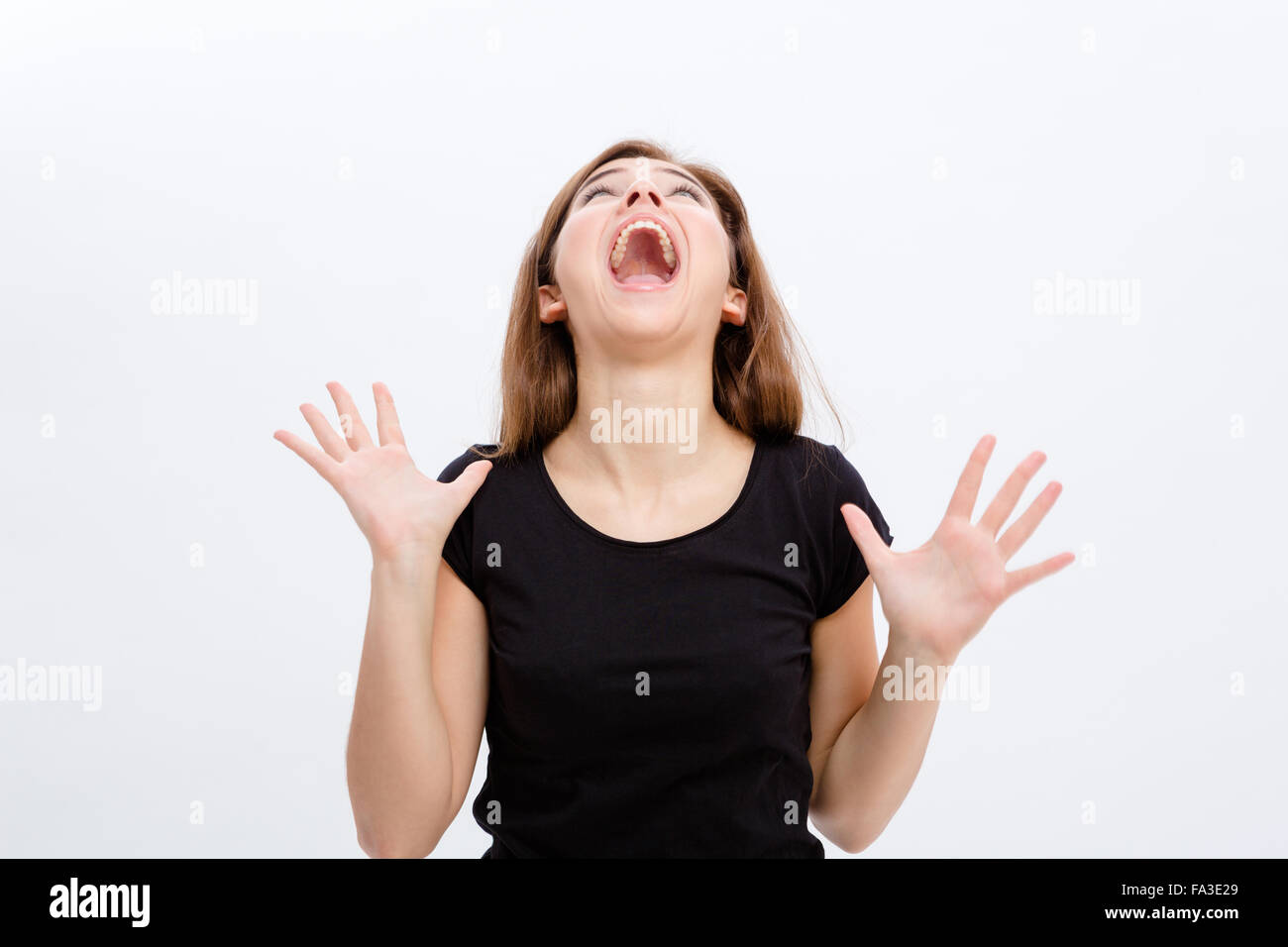 Crazy isterico giovane donna urlare e cercando su sfondo bianco Foto Stock