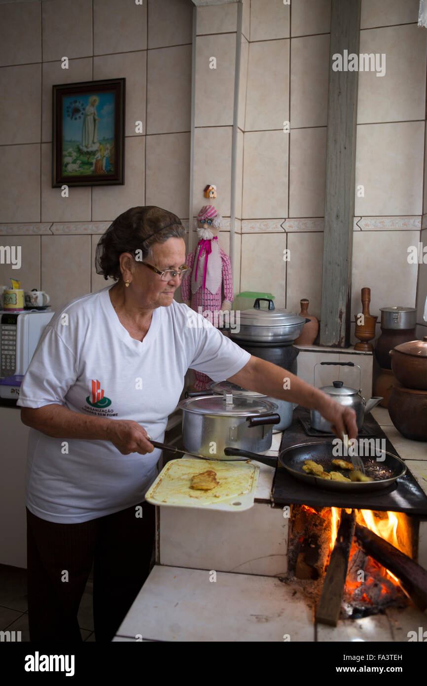 Sud America, Brasile, San Paolo. Una donna locale che cucina il cibo nella sua cucina su un forno a legna tradizionale forno una stufa lenha Foto Stock