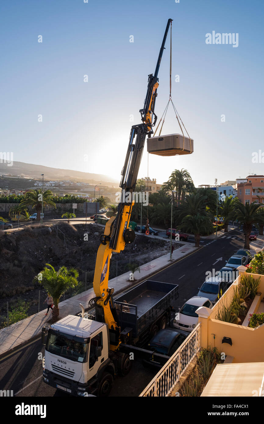 Montata su camion gru di sollevamento di una vasca calda dall'ultimo piano di un palazzo di appartamenti, Playa San Juan, Tenerife, Isole Canarie, Spa Foto Stock