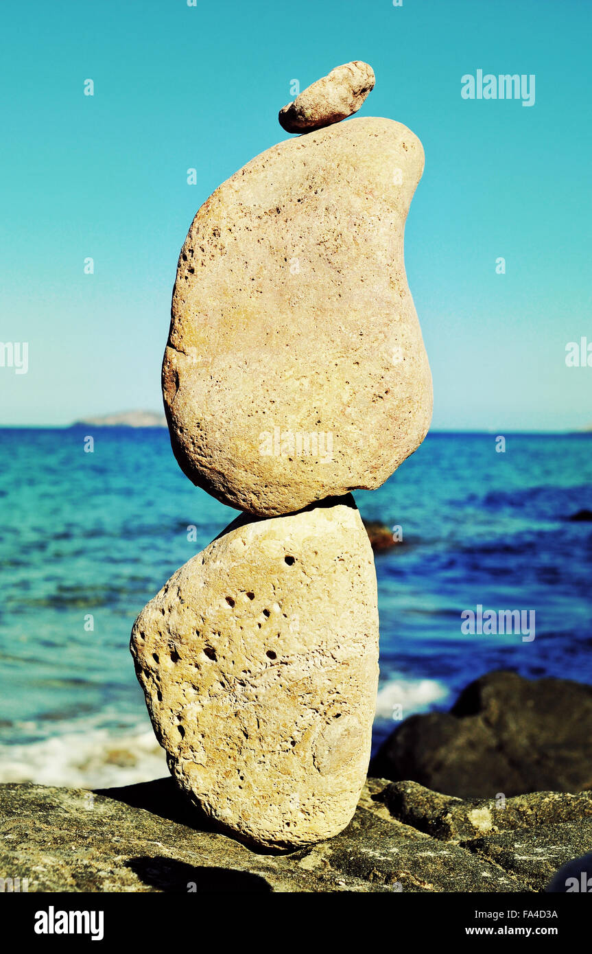 Primo piano di una pila di pietre equilibrato in Isola di Ibiza in Spagna, con il mare Mediterraneo e in background Foto Stock