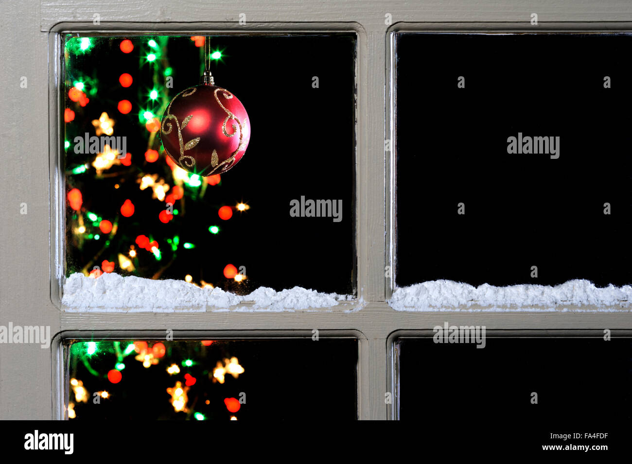 Pallina e albero attraverso la finestra con neve sul telaio. Foto Stock