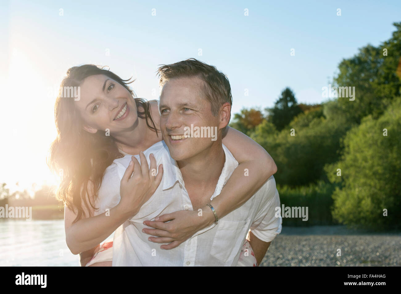 Uomo maturo dando piggyback ride a sua moglie a Lakeside, Baviera, Germania Foto Stock