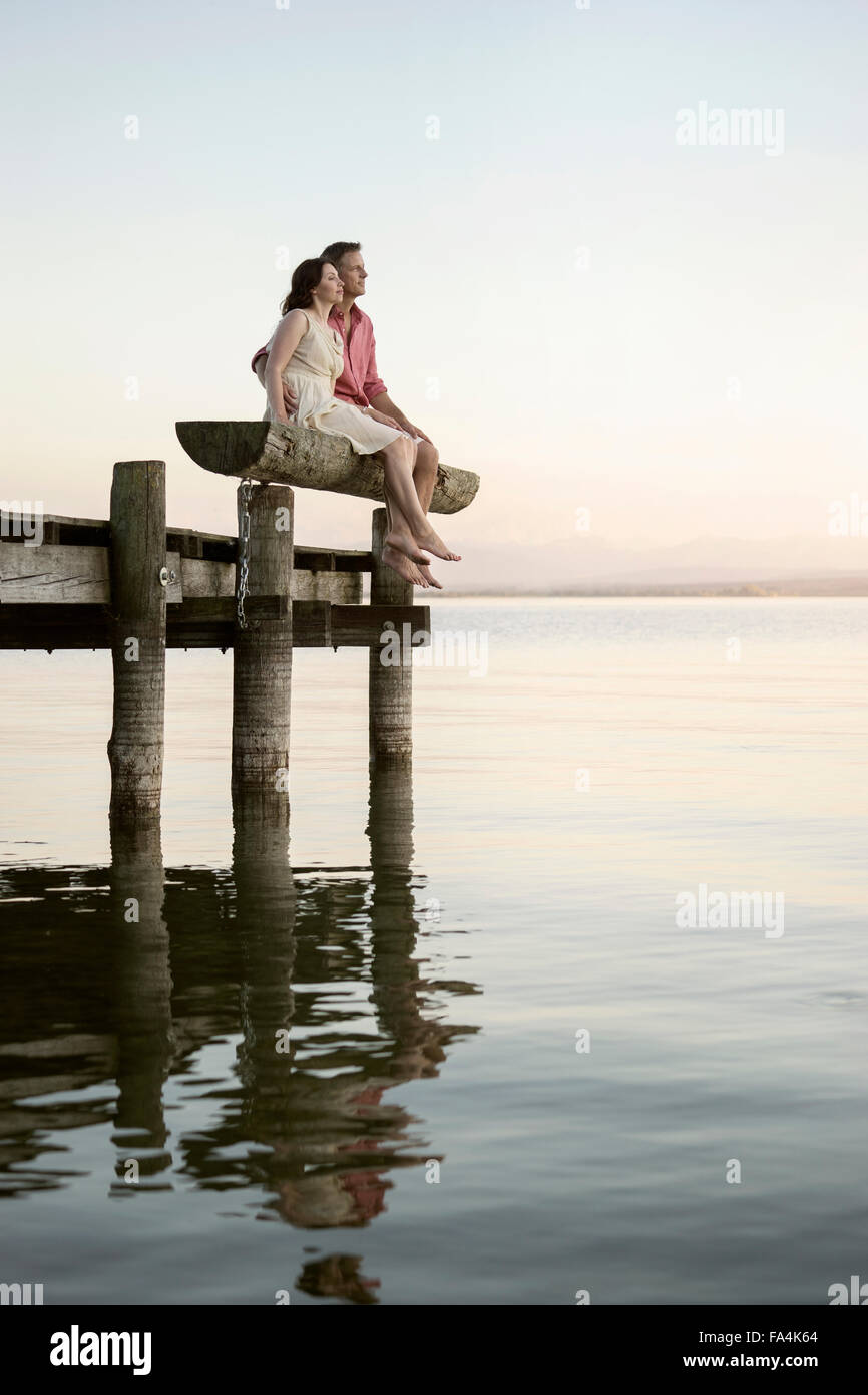 Coppia matura seduta sul molo che si affaccia su un lago, Baviera, Germania Foto Stock