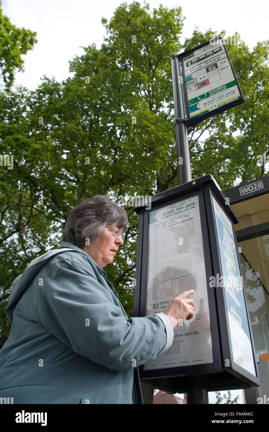 La donna la lettura di un bus tabella di tempo, Foto Stock