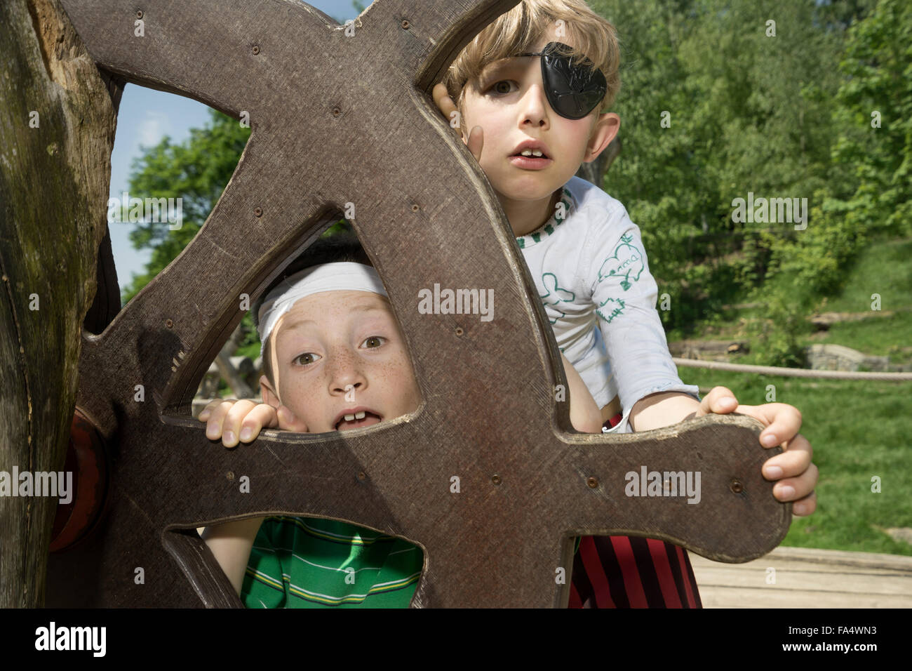 Due ragazzi che trapela dal timone di una nave pirata in parco giochi avventura, Baviera, Germania Foto Stock