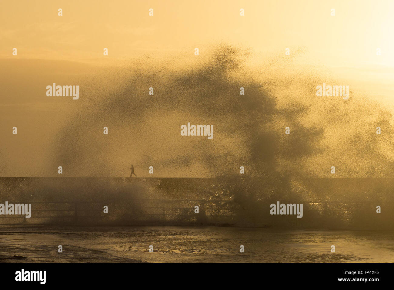 Aberystwyth, Wales, Regno Unito. Il 21 dicembre 2015. Regno Unito: Meteo in mezzo s GOLDEN SUNSET, onde infrangersi sulla parete del porto e un pescatore solitario rapildy rende la sua fuga. Credito: Alan Hale/Alamy Live News Foto Stock