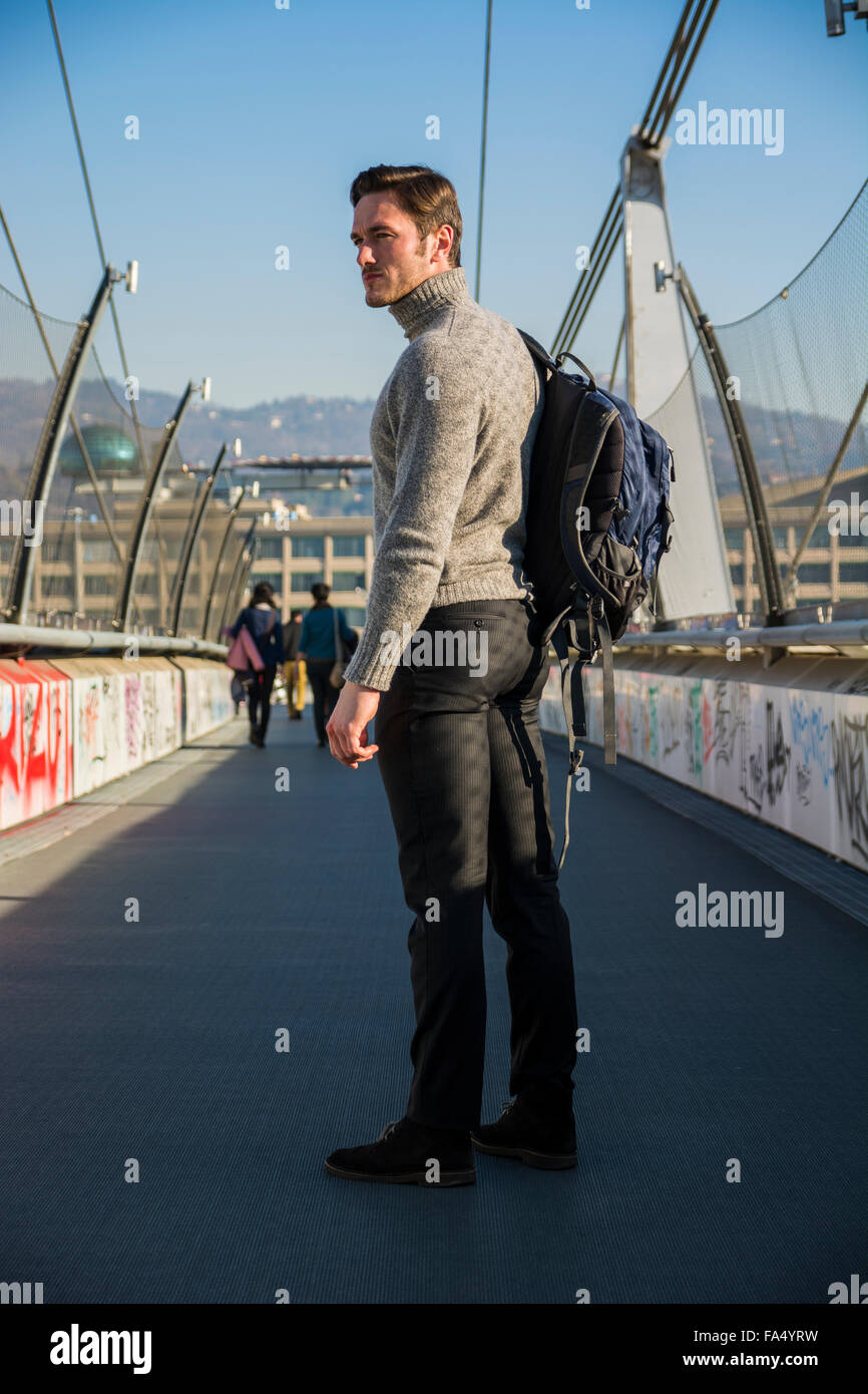 Bel giovane uomo a camminare in città con zaino su di una spalla, indossare  abbigliamento invernale a piena lunghezza shot Foto stock - Alamy