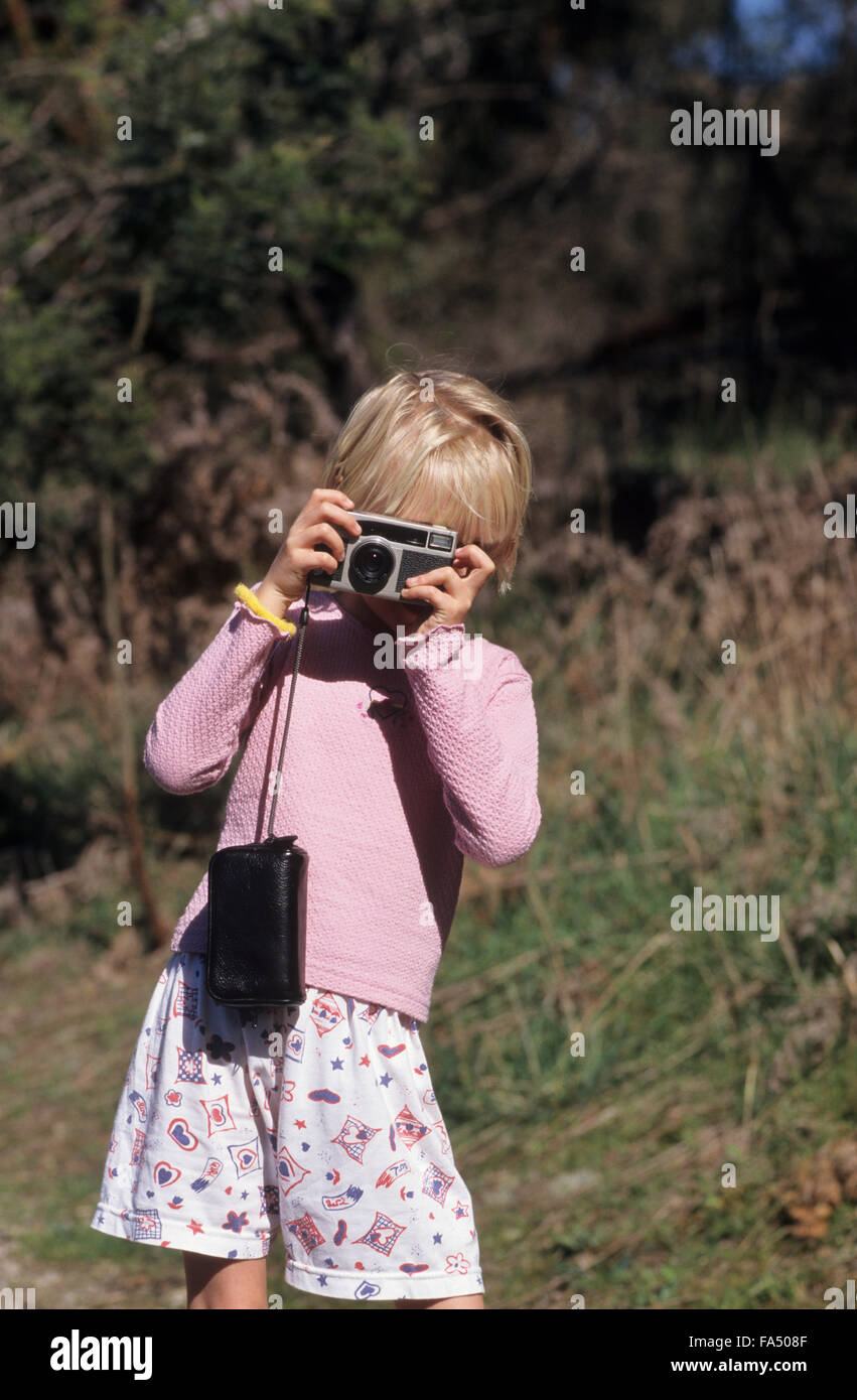 Ragazza giovane circa 7 prendere una fotografia usando una vecchia fotocamera a pellicola. Foto Stock