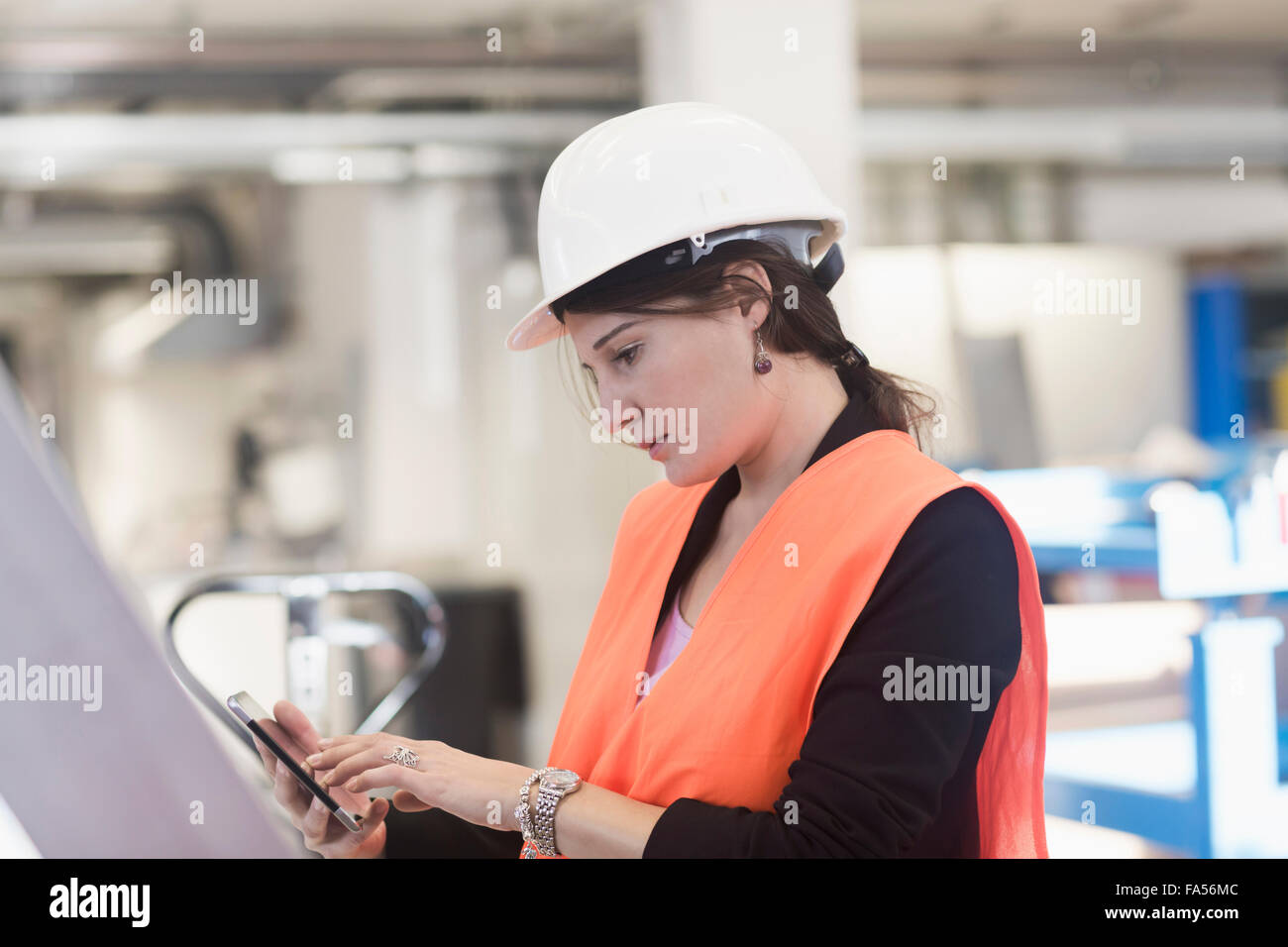 Ingegnere femmina utilizzando un telefono intelligente in un impianto industriale di Freiburg im Breisgau, Baden-Württemberg, Germania Foto Stock