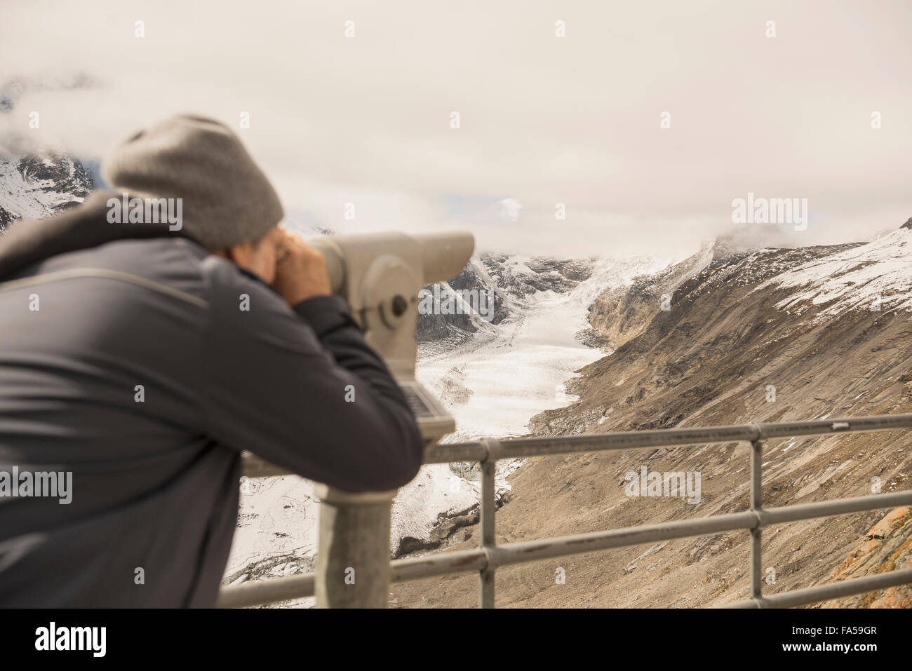 Uomo maturo guardando a vista con il telescopio, ghiacciaio Pasterze, Parco Nazionale Hohe Tauern, Carinzia, Austria Foto Stock