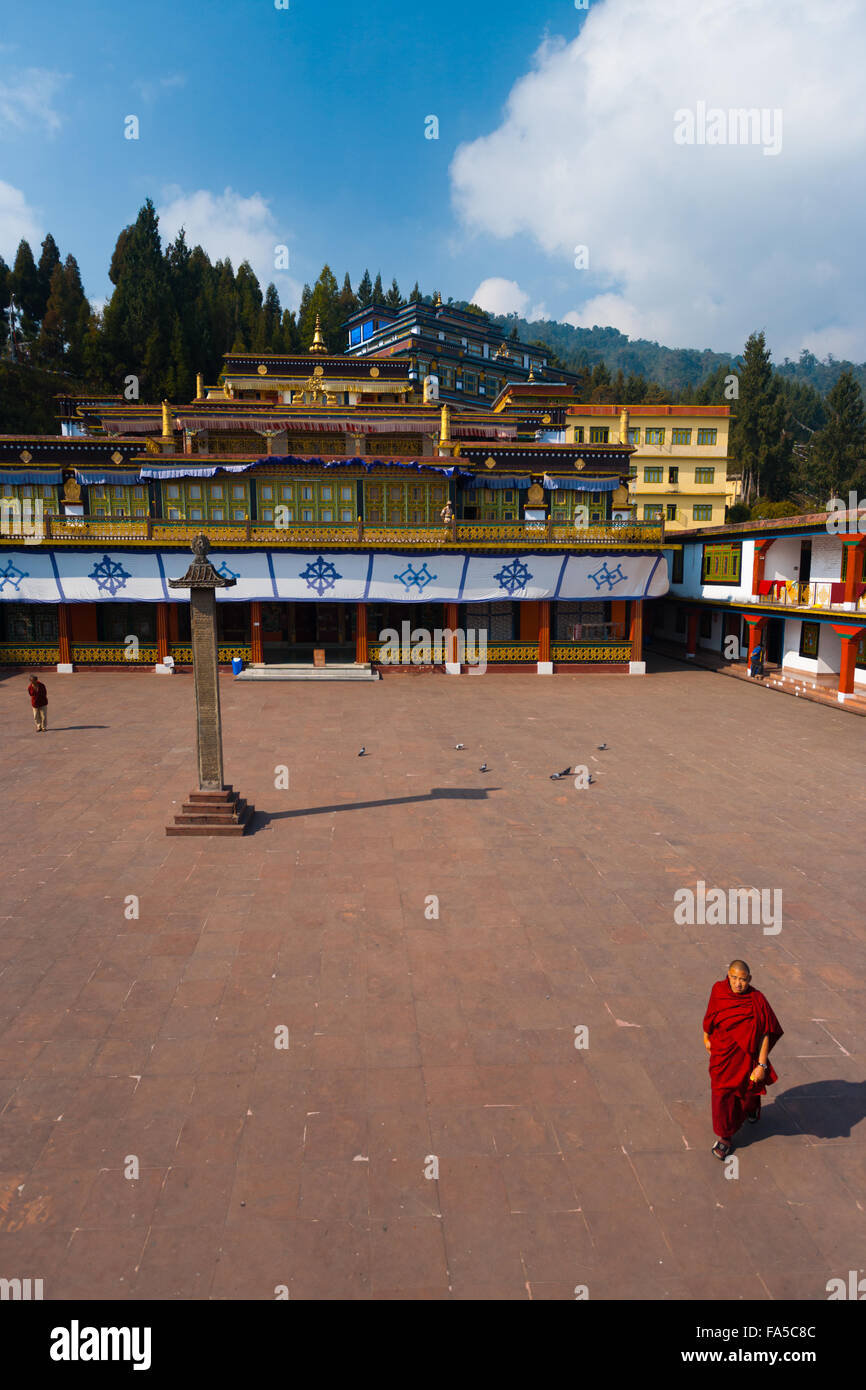 Un Monaco a piedi attraverso l'ampio cortile del monastero di Rumtek, sede del Karmapa su un chiaro soleggiato, cielo blu giorno Foto Stock
