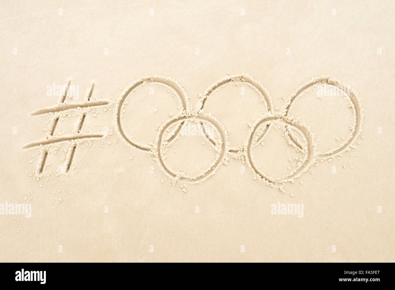 RIO DE JANEIRO, Brasile - 10 novembre 2015: hashtag manoscritta social media messaggio per Rio 2016 Olimpiadi con anelli in sabbia. Foto Stock