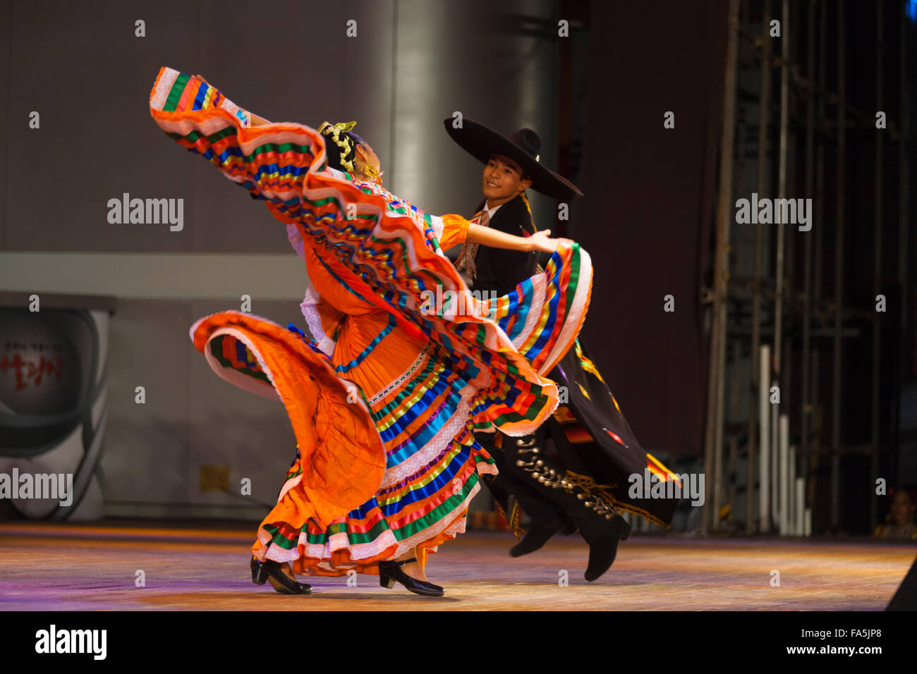 Ballerino femmina in colorate arancio ripetutamente il vestito di torsione e svolazzanti bracci durante il Mexican Hat dance, folclore tradizionale Foto Stock