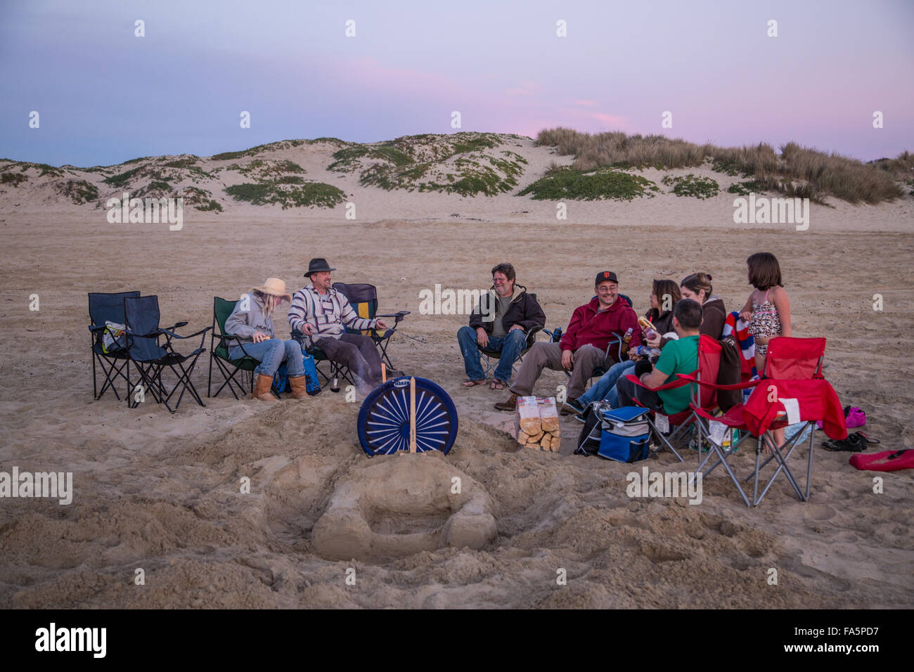 Un gruppo di amici gustando un barbecue e il tramonto a Pismo Beach, California. Foto Stock