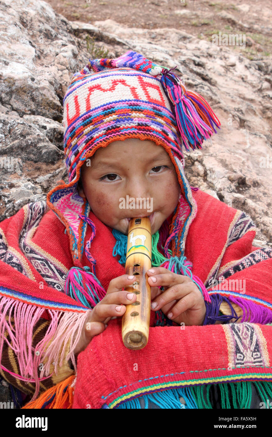 Ragazzo peruviano in abito tradizionale Riproduzione di un flauto di legno Foto Stock