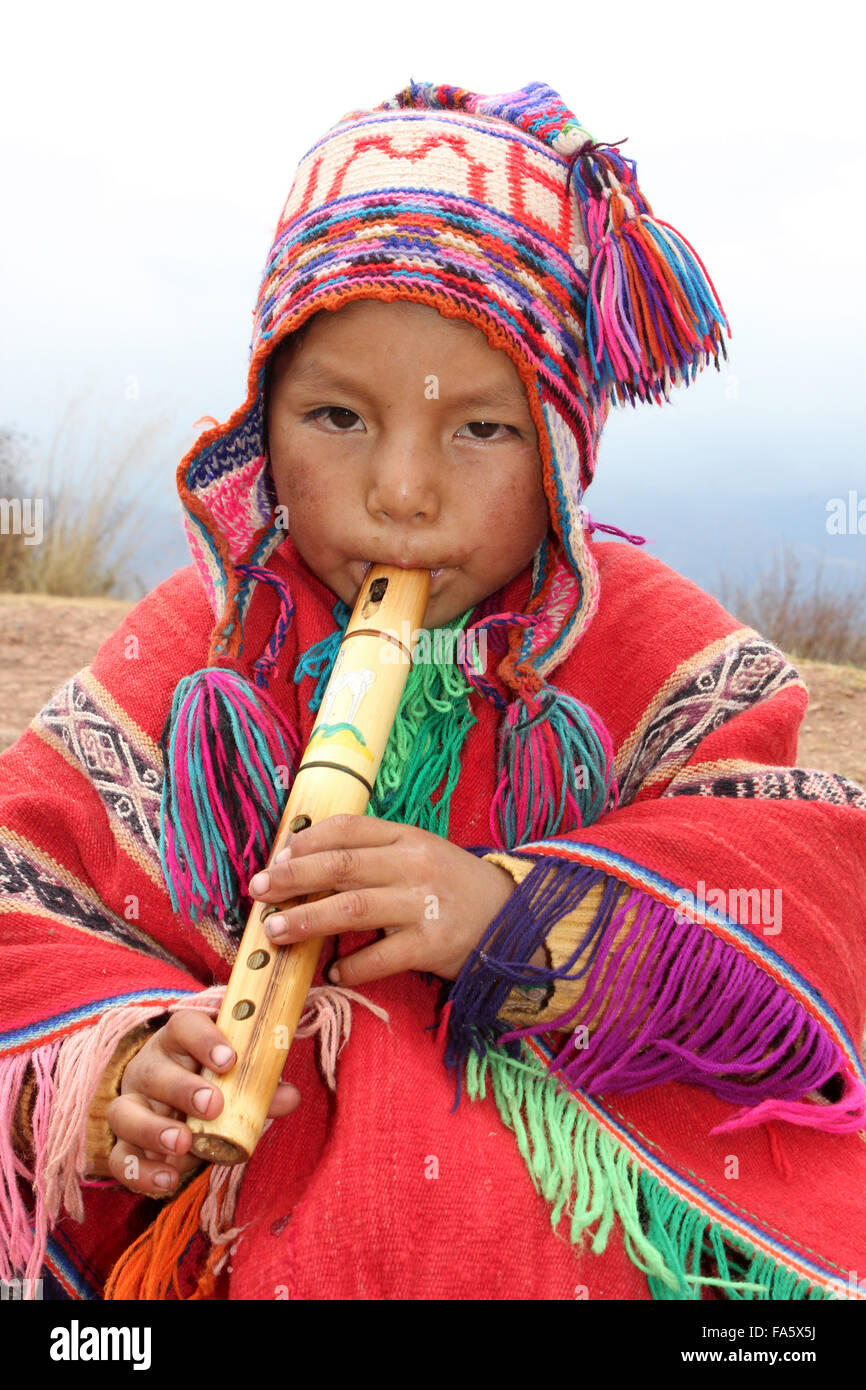 Ragazzo peruviano in abito tradizionale Riproduzione di un flauto di legno Foto Stock