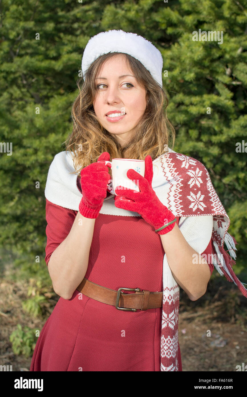 Bellissima Santa Claus girl avente tazza di tee all'aperto davanti grosso abete Foto Stock