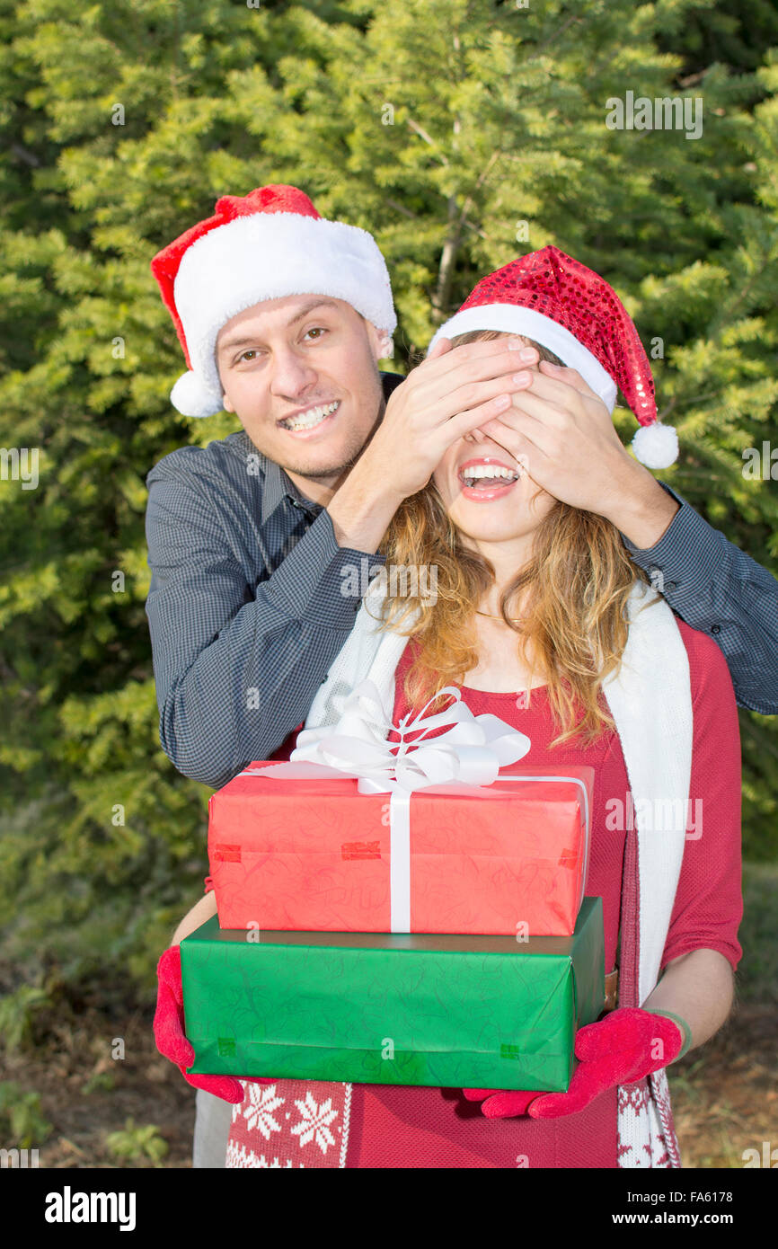 Ragazzo sorprendente una ragazza con il regalo di Natale all'aperto Foto Stock