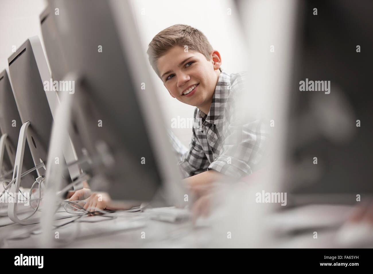 Una scuola di computer in camera in laboratorio o in laboratorio con righe di monitor per computer e posti a sedere. giovane seduto a lavorare al terminale. Foto Stock