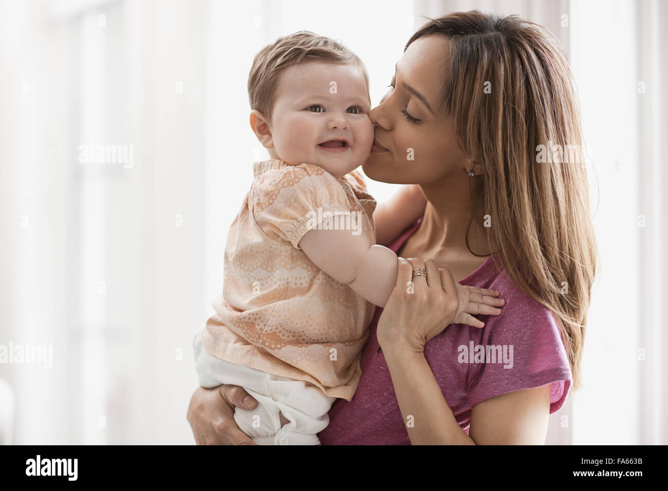 Una madre e figlia di una donna tenendo un bambino, il bacio sulla guancia. Foto Stock