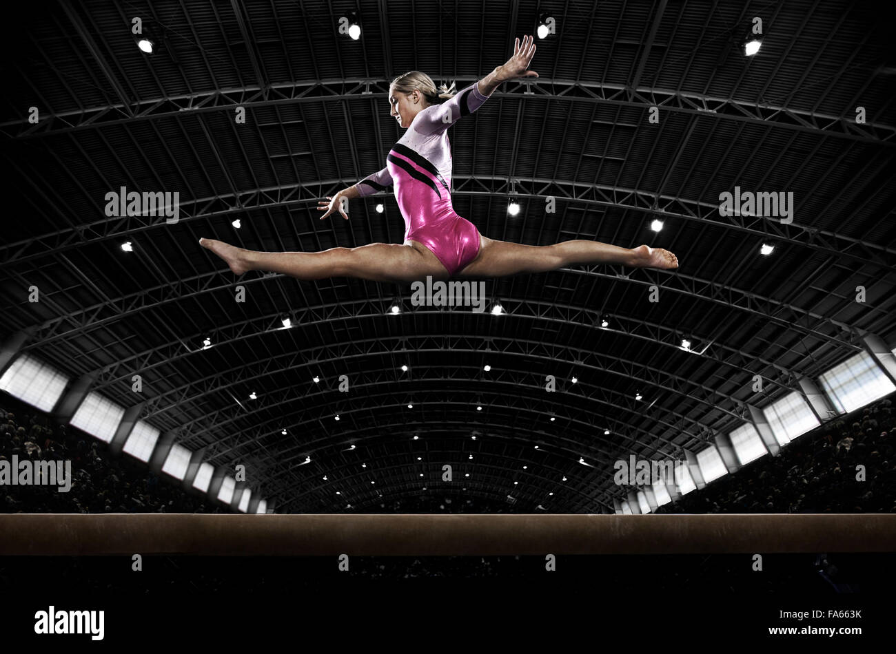 Una giovane donna ginnasta eseguendo sulla trave, in equilibrio su un pezzo ristretto di apparecchiatura. Foto Stock