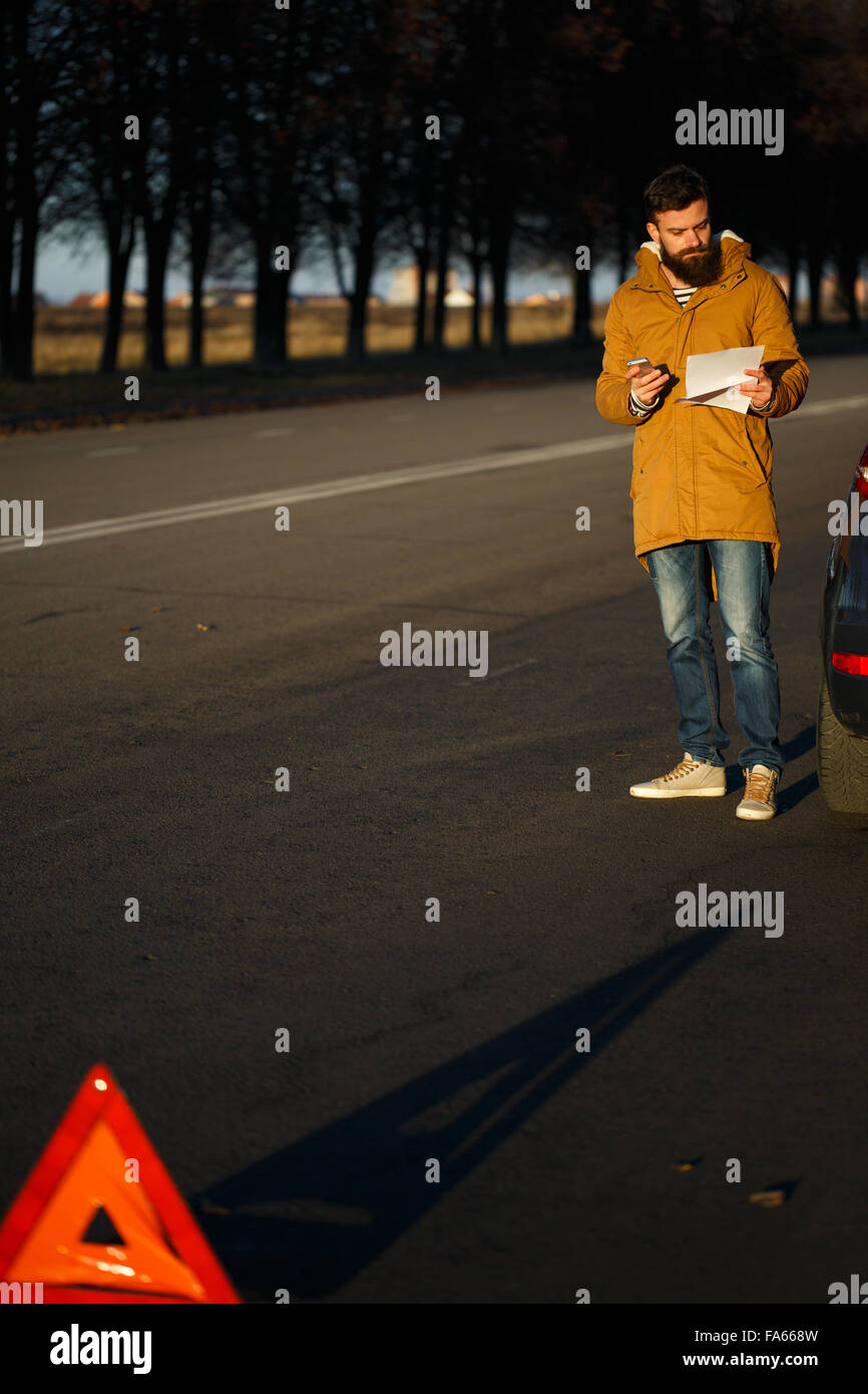 Autista uomo esaminando danneggiato automobili automobili dopo la rottura Foto Stock