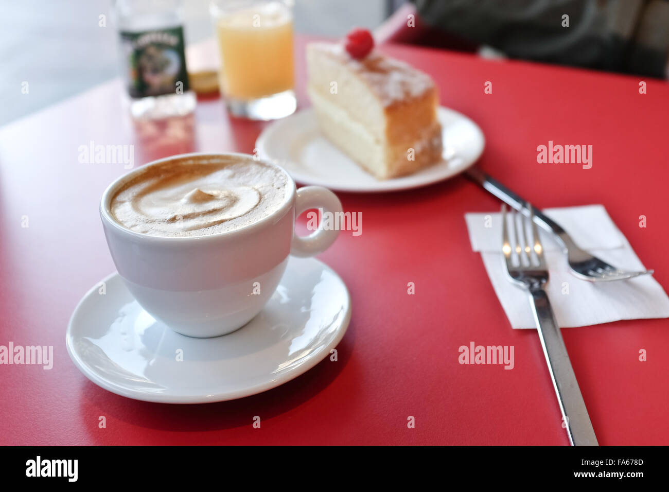 Un cappuccino e una fetta di torta sul tavolo Foto Stock