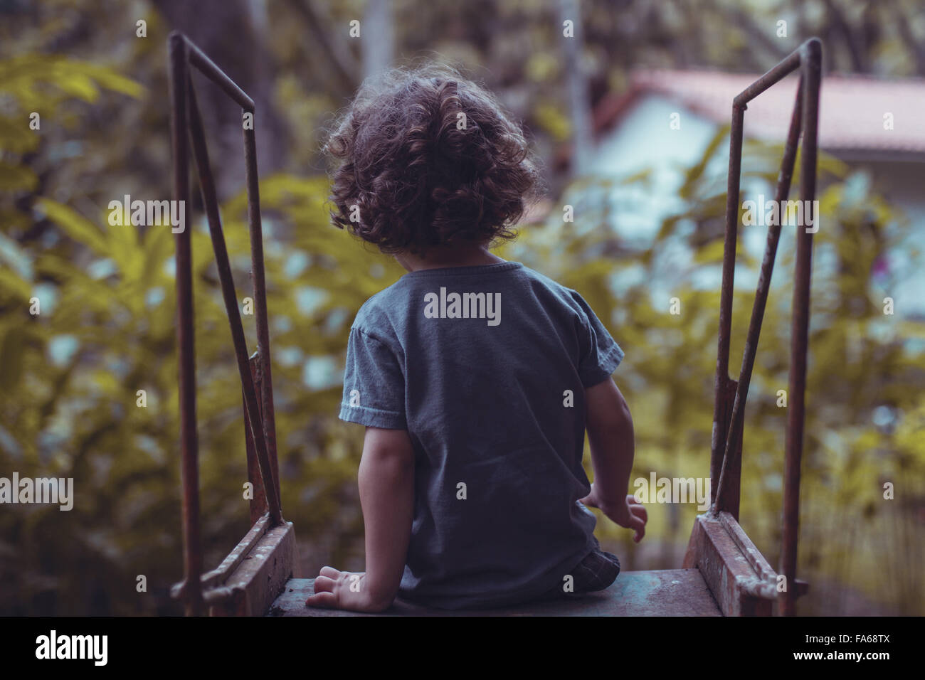 Vista posteriore di un ragazzo di localizzazione su una slitta al parco giochi Foto Stock