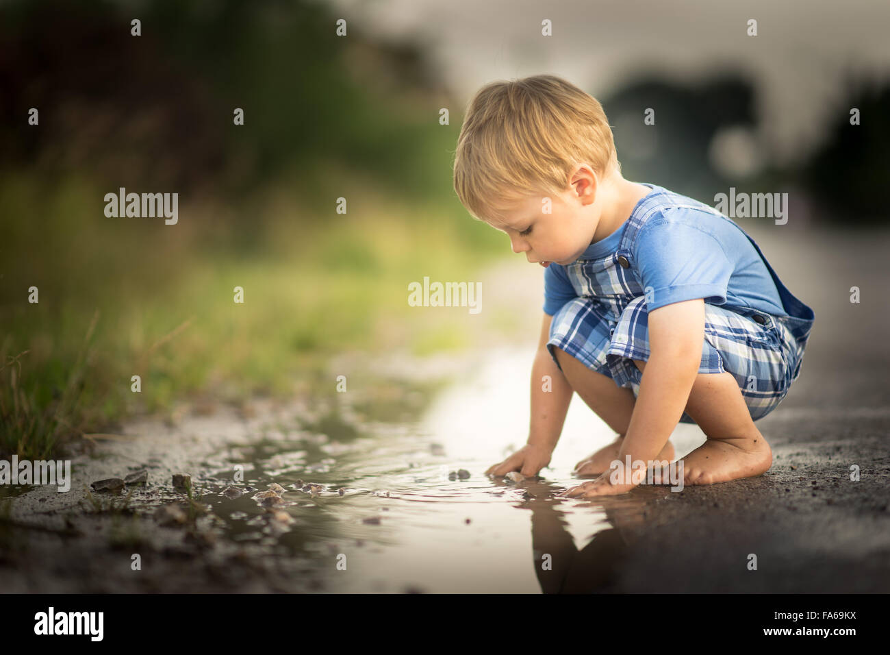 Ragazzo giocando in una pozza d'acqua Foto Stock