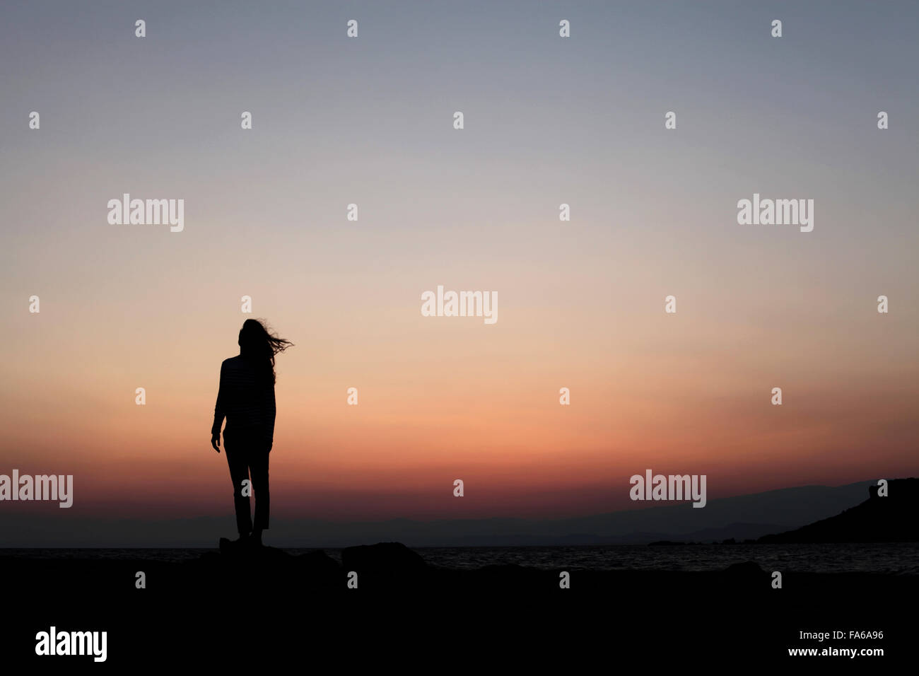 Silhouette di una donna in piedi all'aperto al tramonto Foto Stock