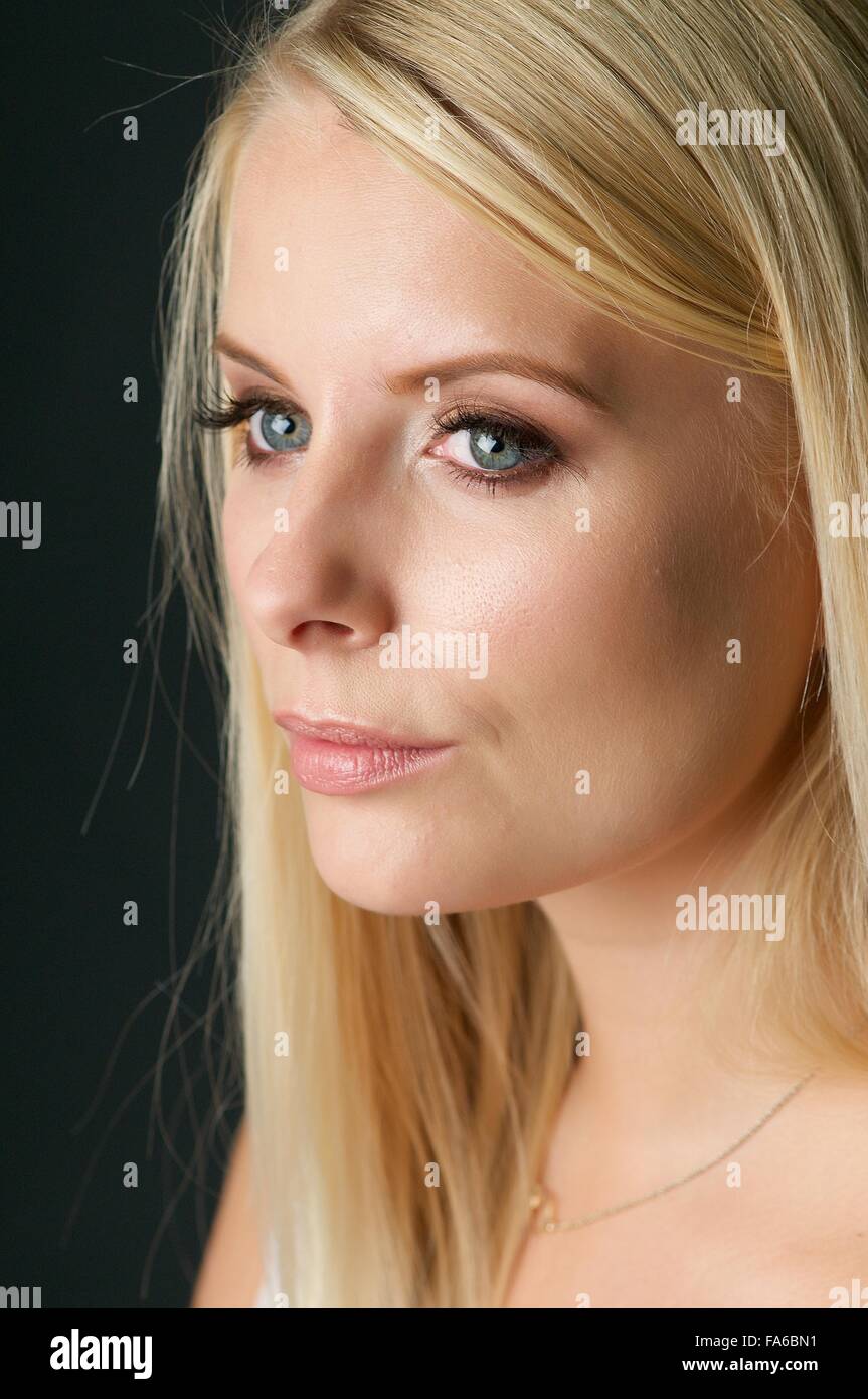 Una ragazza bionda in una low cut luce rosa top siede in studio Foto Stock