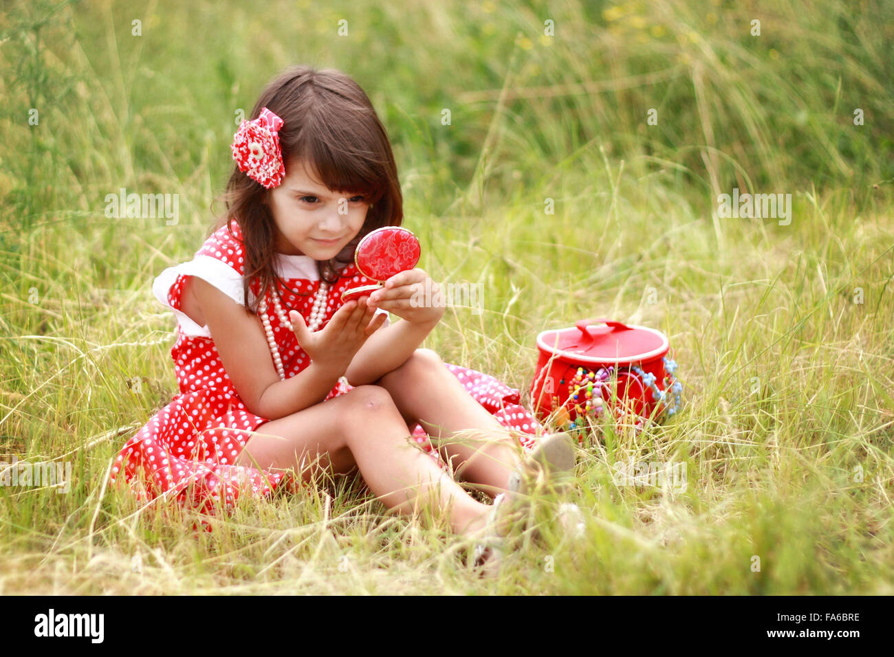 Ragazza seduta su erba cercando in mano lo specchio Foto Stock