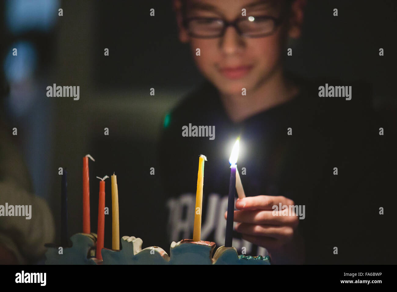 Ragazzo adolescente Menorah illuminazione durante Hanukkah Foto Stock