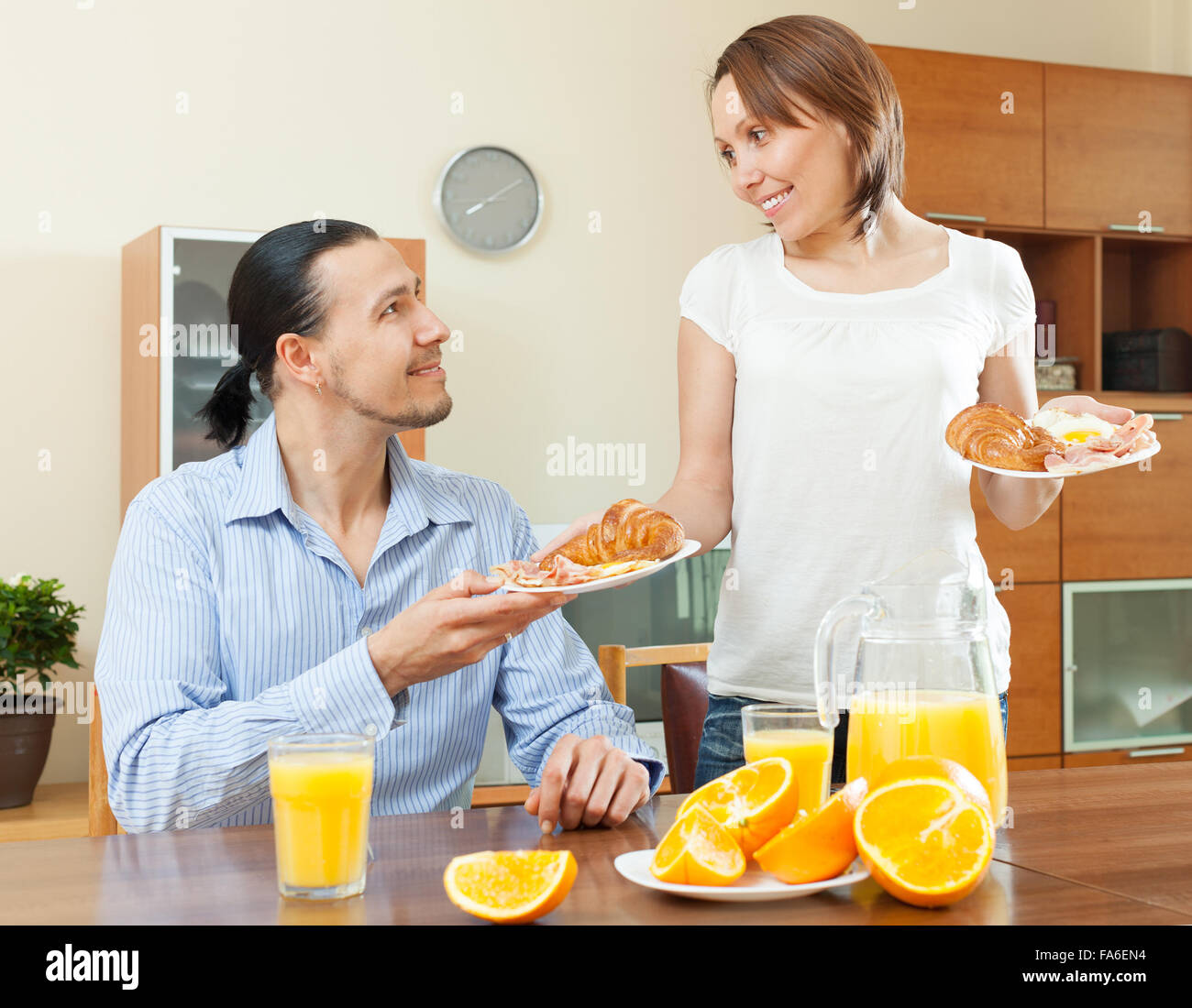 Donna sorridente serve la colazione con il suo amato uomo in mattinata Foto Stock