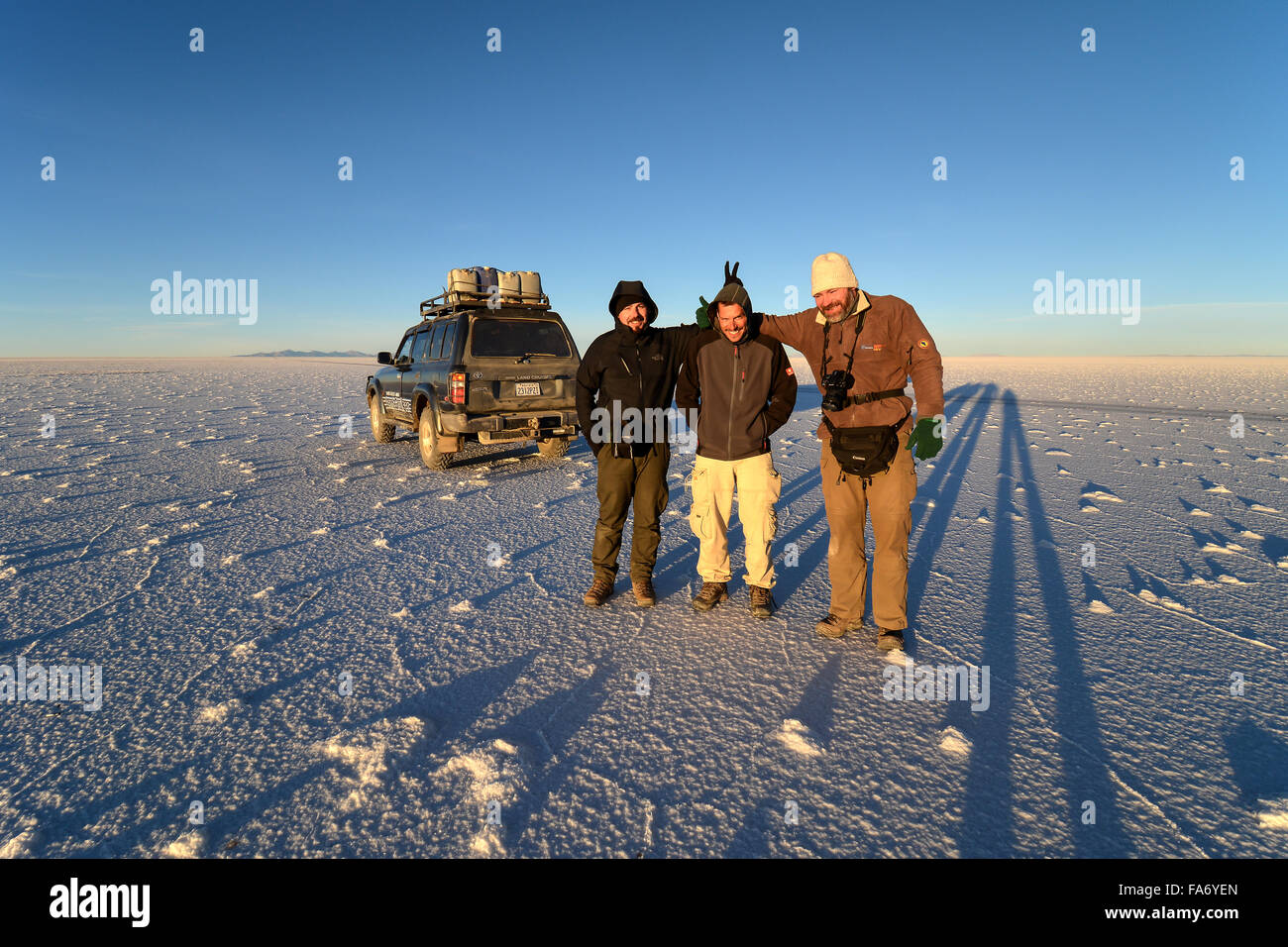 Tre uomini e suv sulla distesa di sale, Salar de Uyuni, altiplano, Bolivia Foto Stock