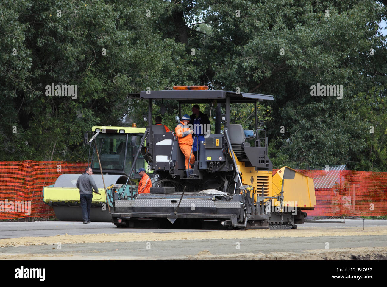 Lavoratori e macchina per pavimentazione stradale sito in costruzione Foto Stock