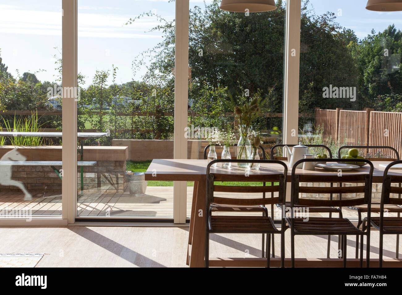 La cucina e la zona pranzo tavolo e sedie con ciondolo illuminazione in casa residenziale, Cambridge. Una casa combinando stile moderno minimalista con la visualizzazione di oggetti tradizionali utilizzate nella vita di ogni giorno. Foto Stock