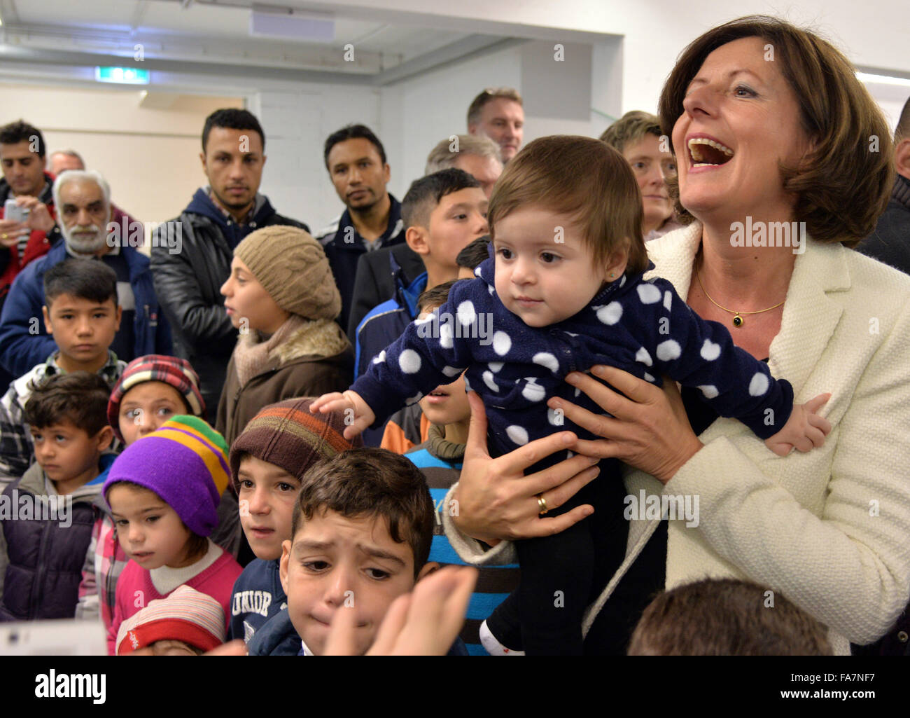 Kastellaun, Germania. 23 Dic, 2015. Malu Malu Dreyer (R), Premier dello Stato tedesco della Renania Palatinato, trattiene il ten-mese-vecchio Elen Youssef dalla Siria nelle sue braccia durante le celebrazioni del Natale con i rifugiati e i bambini e le loro famiglie come pure i membri della Croce Rossa tedesca (DRK) in Kastellaun, Germania, 23 dicembre 2015. Foto: HARALD TITTEL/dpa/Alamy Live News Foto Stock