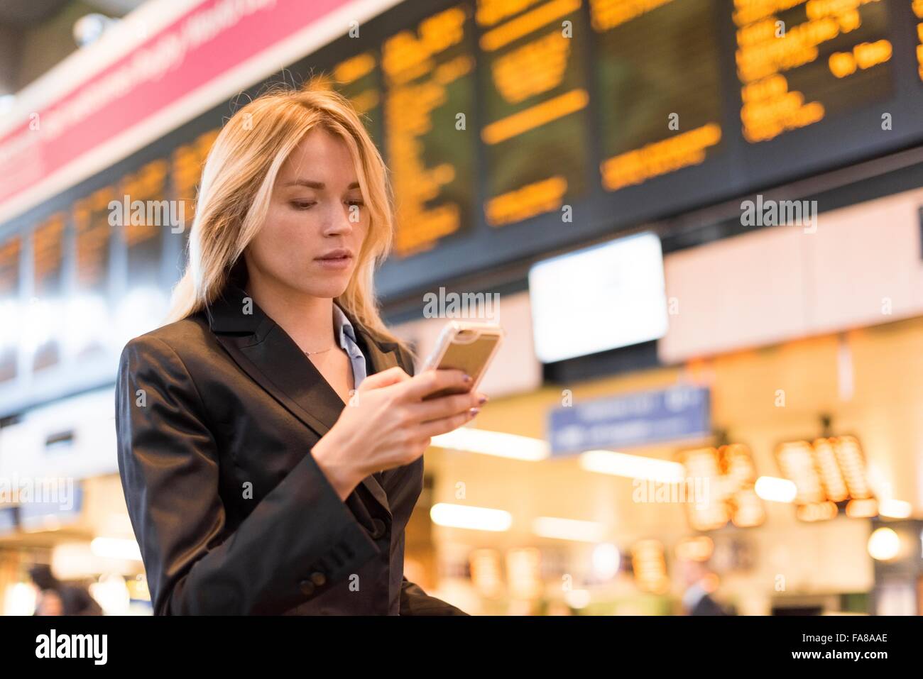 Giovane imprenditrice nella stazione ferroviaria di lettura di testi dello smartphone Foto Stock