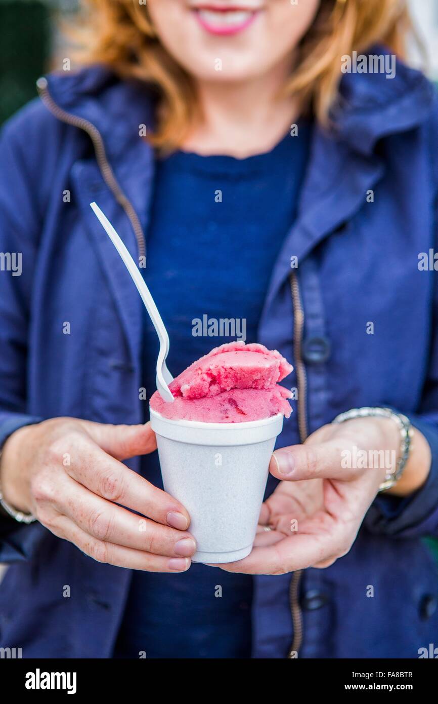 Ritagliato colpo di donna matura azienda rosa gelato nella tazza monouso Foto Stock