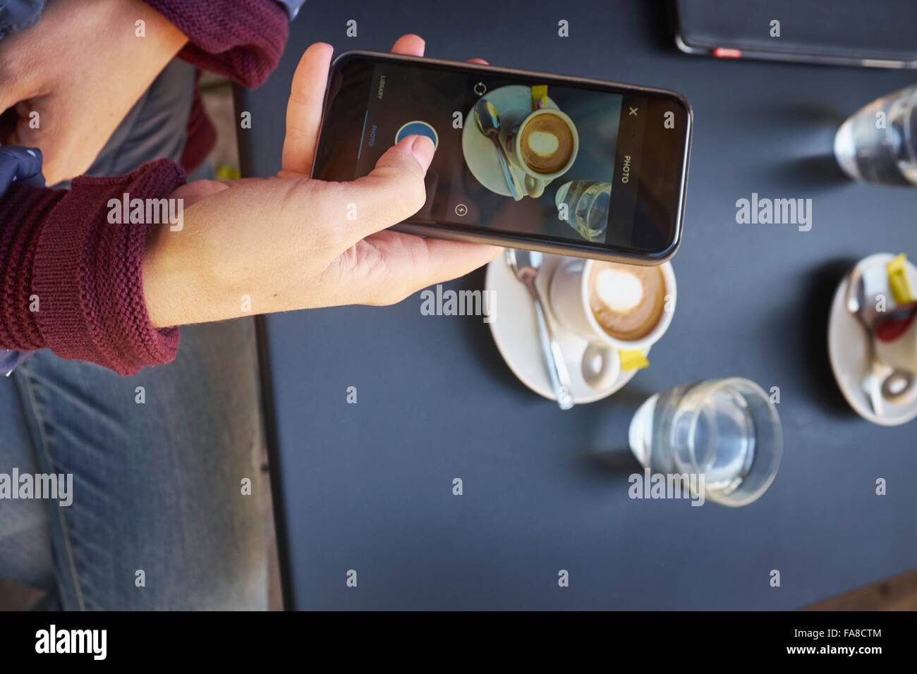 Vista aerea della metà donna adulta di fotografare la tabella sullo smartphone al cafè sul marciapiede Foto Stock