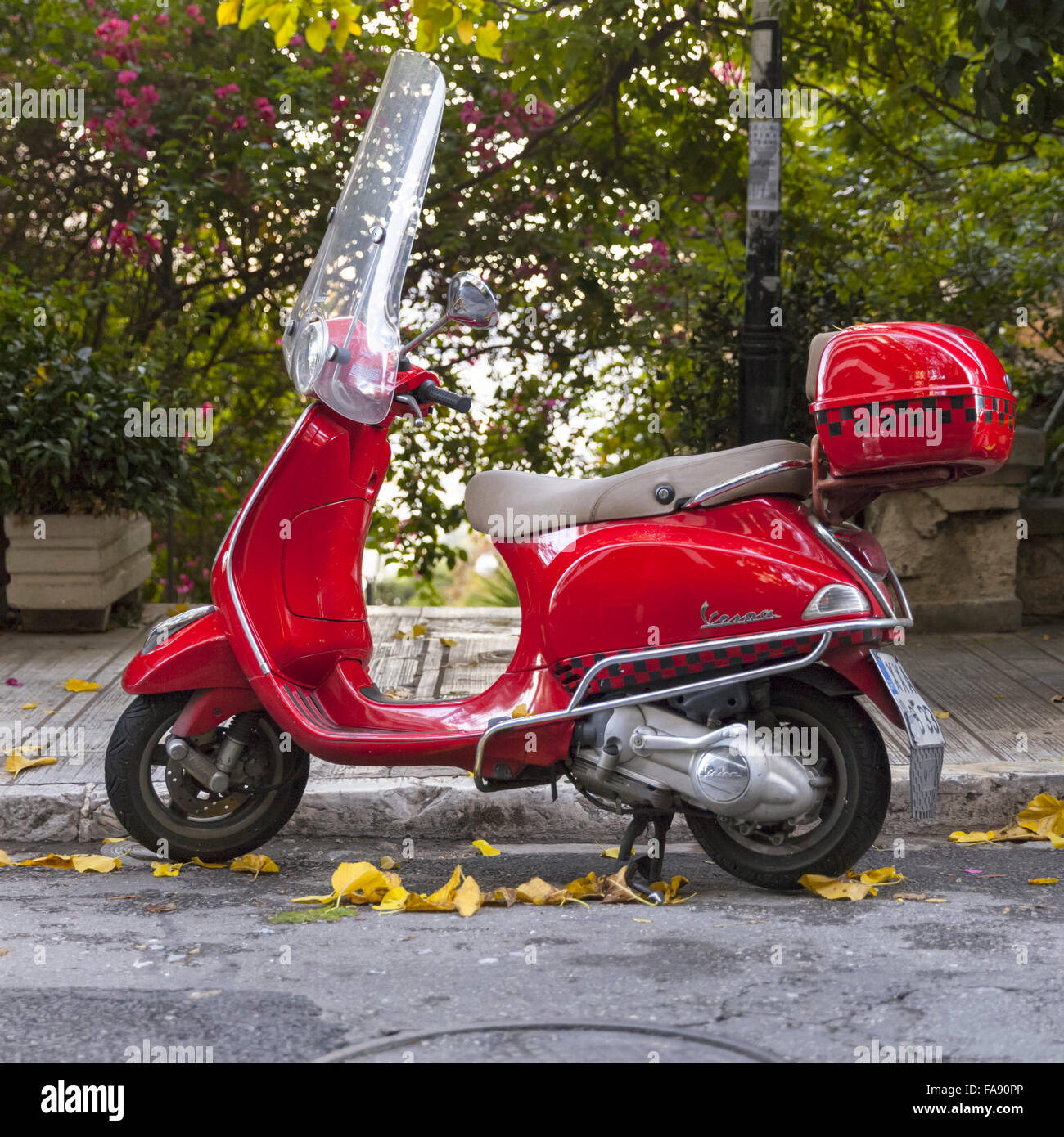 Red Piaggio scooter Vespa parcheggiata in una strada tranquilla nella zona di Kolonaki di Atene, Grecia Foto Stock