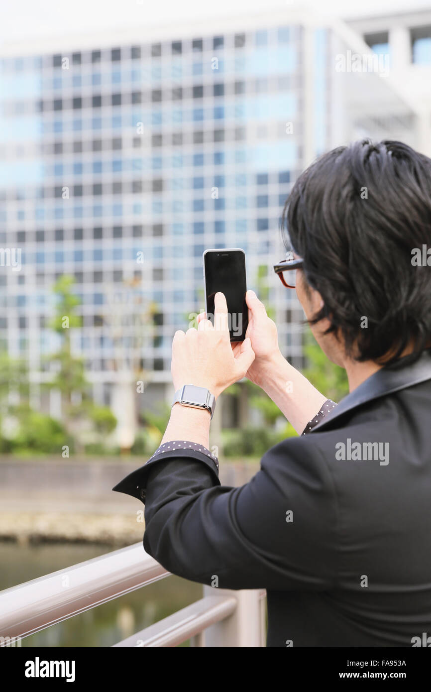Imprenditore giapponese con smart indossabile guarda e lo smartphone Foto Stock